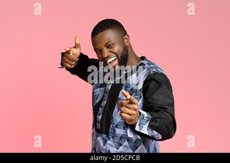Handsome black young man in traditional costume indicating to camera Stock Photo