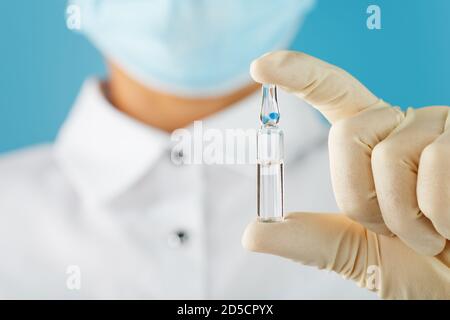 In the hands of a research scientist, a doctor in rubber gloves, an ampoule with a vaccine close-up. Stock Photo