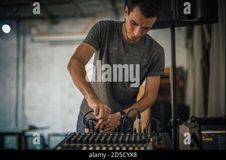 Behind the scene. Sound technician electric engineer adjusting sound elements backstage. Control audio panel. Audio mixing console Stock Photo