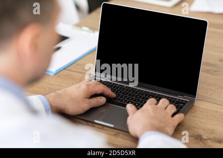 Man working on laptop with empty black screen for mockup Stock Photo
