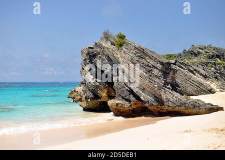 Volcanic rock at the Pink beach in Bermuda.Natural beauty of Horseshoe Bay Beach.Pink sand,clear blue sky,turquoise water and volcanic rocks. Stock Photo