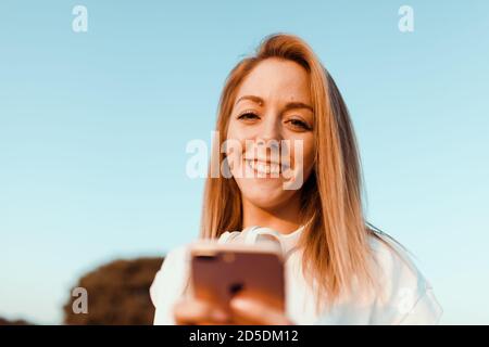 Young woman taken notes on her smartphone in the field Stock Photo
