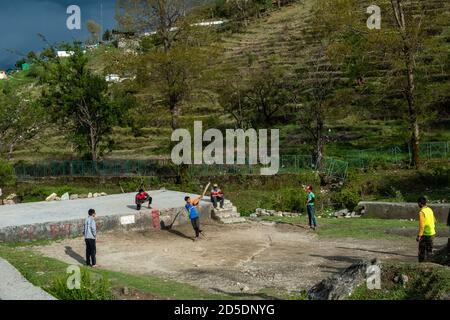 Munsyari, Uttarakhand, India - April 2019: Young Indian boys playing cricket on a playground in the Himalayan village of Munsyari. Stock Photo