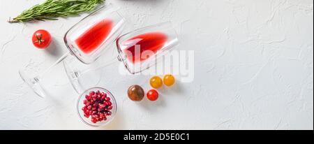 Two glass of red wine near herbs for grill over white concrete table top view. Big banner size. Space for text. Stock Photo