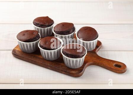 Many sweet tasty chocolate cupcakes on wooden cutting board Stock Photo