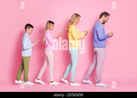 Full length profile side photo of daddy mommy small kids texting on cellphone isolated over pink pastel color background Stock Photo