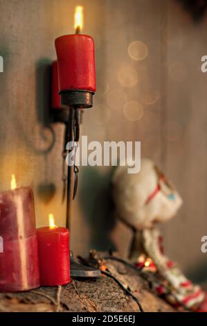 New Year card with blurred bright bokeh wooden background. Red candles are burning, standing in black candlesticks. Silhouette of a vintage doll. Stock Photo