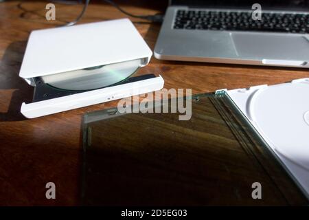 An external CD / DVD reader / writer attached to a laptop via USB - used to read or write to CDs and DVDs. Stock Photo