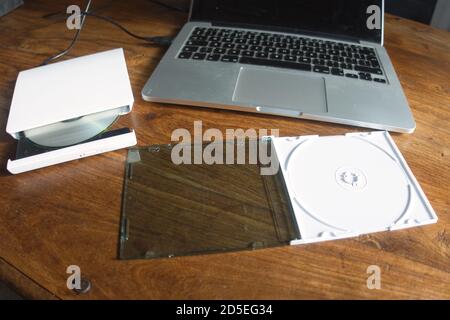 An external CD / DVD reader / writer attached to a laptop via USB - used to read or write to CDs and DVDs. Stock Photo