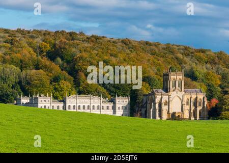 Milton Abbas, Dorset, UK.  13th October 2020.  UK Weather.  The woodland trees are in their full autumn colours behind the historic Milton Abbey at Milton Abbas in Dorset on an afternoon of warm sunny spells.  Picture Credit: Graham Hunt/Alamy Live News Stock Photo
