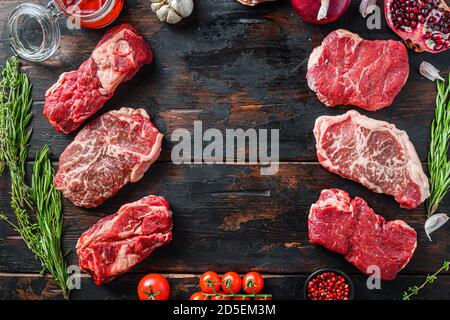 Meat beef steaks frame concept, with different steak cuts on dark old wooden table top view with space for text. Stock Photo