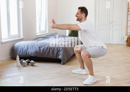 Man Doing Two-Legged Squat Exercise Training At Home Stock Photo