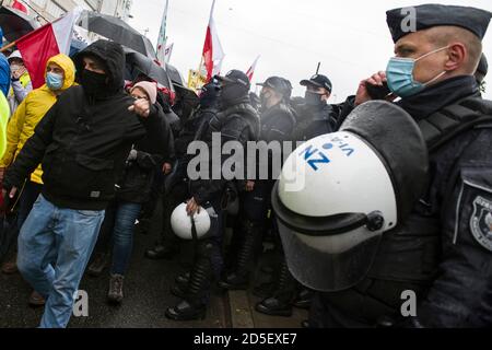 Riot police watching over the protesting farmers during the march.To oppose the so-called 'Five for animals' act (Piatka dla zwierzat), Agrounia, the farmers' organisation lead by Michal Kolodziejczak marched through the streets, paralyzing public transport. It is estimated that 70 thousand people took part in the protest. Stock Photo