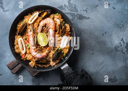 Paella with seafood, prawns, musselsm chicken and rice in pan on grey textured background, top view with space for text Stock Photo