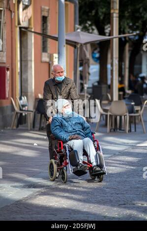 terni ,italy october 13 2020:man pushing another man on wheelchair both with medical mask Stock Photo