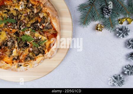 Flat lay of pizza spinning 360 degree rotation on wooden salver, Christmas decorations around. Concept of discount and promotion in a pizzeria. Copy s Stock Photo