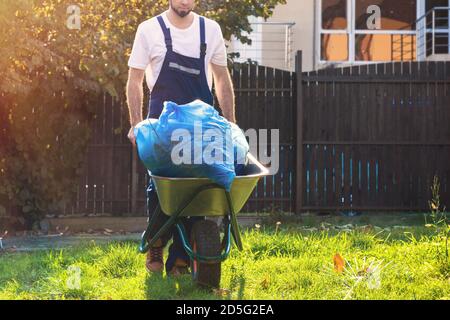 The gardener rolls a cart with bags of leaves. Cleaning the yard. Close up. Stock Photo