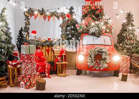 Magic card in red color. Decorated retro car with festive New Year lights, garlands, branches of Christmas trees, gift boxes in white-green wrapping Stock Photo