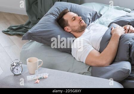 Man Sleeps In Bed After Taking Sleeping Pills In Bedroom Stock Photo