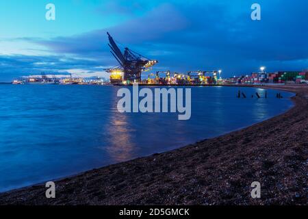 Port of Felixstowe, Suffolk, cranes loading containers onto cargo ships at dusk Stock Photo
