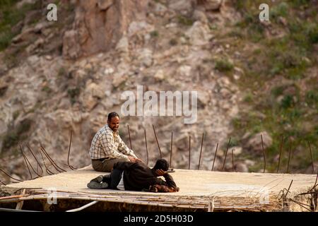 Dana, Jordan 04/01/2010: Two Arabic construction workers are resting on the flat concrete roof of a building . Metal beams penetrate from the sides an Stock Photo
