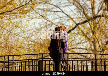 Oxford, UK 03/19/2011: A young couple is kissing on a bridge in a park. They wear casual clothes and  the boy puts his arms around his girlfriends sho Stock Photo