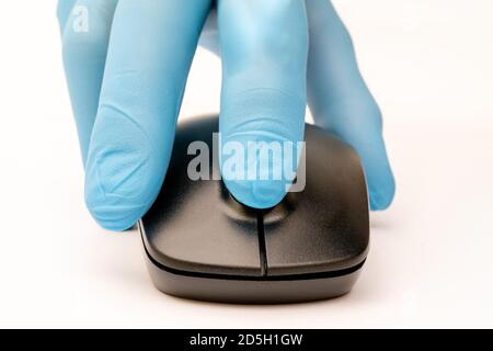 Black computer mouse in a man's hand in a blue medical glove. Stock Photo