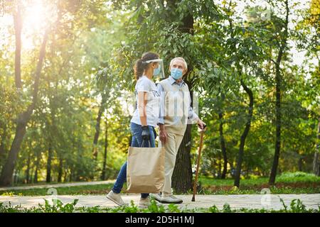 Happy person in casual clothes and protective medicine mask walking through the park Stock Photo