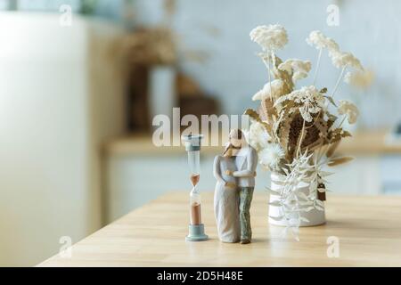 .Dried flowers in a vase on the table next to the hourglass and the statuette Stock Photo
