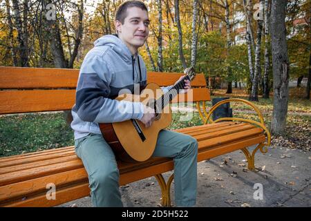 guy plays guitar in city park outdoor Stock Photo