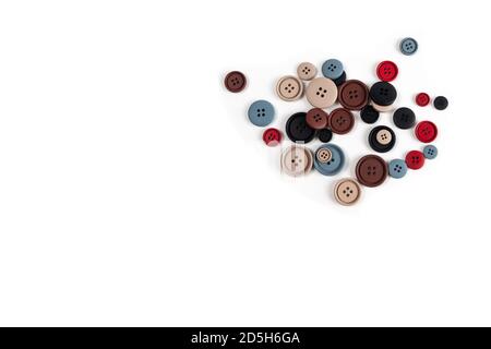 Pile of color brown, beige, grey, red, black plastic matte buttons on white, beautiful needlework, minimalism. Use for sewing. Space for text. Stock Photo