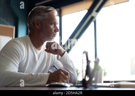 Casual Grey-haired businessman looking through paper documents. Male accounting manager reviewing financial report Stock Photo