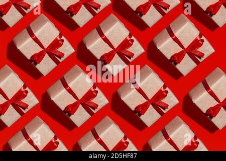 pattern gift box in kraft paper with red ribbon bow insulated on red background, top view on the festive background. Stock Photo