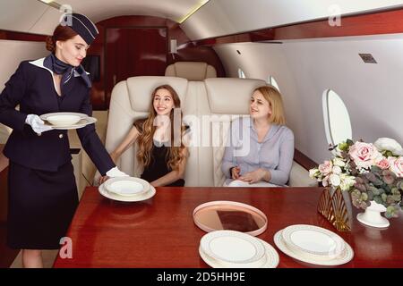 The flight attendant serves the passengers of the business jet. Stock Photo