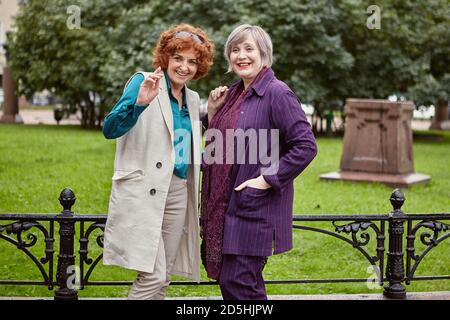 Two smiling senior women of European appearance are having a cheerful conversation outdoors. Stock Photo