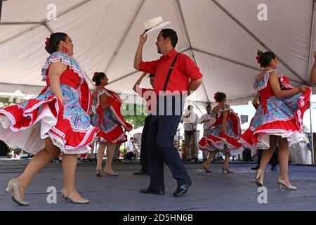 Couples dressed in traditional costumes play on the stage in the center with boys leading girls in San Juan,Puerto Rico. Stock Photo