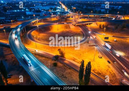 Intersection transport junction at night city road with bridges and car traffic, aerial view. Stock Photo