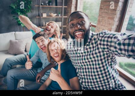 Four crazy fellows men gathering sit comfort cozy couch enjoy travel holiday make selfie show thumb up sign joke v-sign imaginary rabbit ears blogging Stock Photo