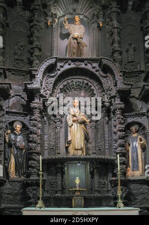 Lima, Peru - December 4, 2008: Closeup of blackened, sculptured reredos behind altar at Cathedral showing four statues of saint, including Mother Mary Stock Photo