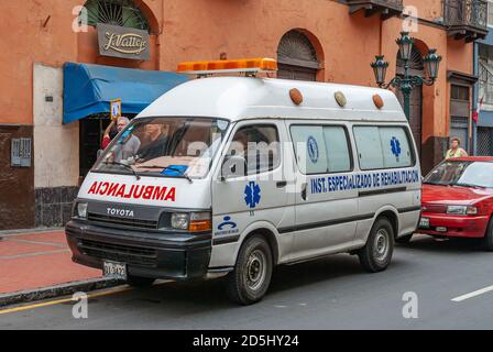 Lima, Peru - December 4, 2008: Closeup of white ambulance van in street. Orange-brown facade as backdrop. Stock Photo