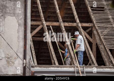 BELGRADE, SERBIA - AUGUST 8, 2018: Old Construction workers, roofers and tilers, replacing and renovating the roof of a house with tiles while wooden Stock Photo