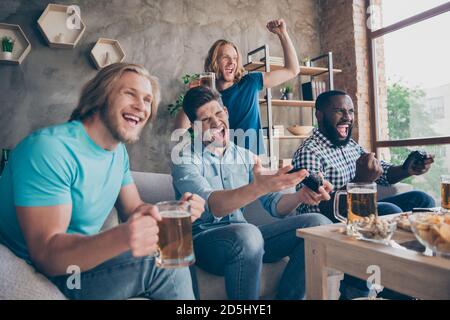 Portrait of four nice attractive cheerful cheery ecstatic guys playing video game sport battle contest having fun spending weekend at industrial loft Stock Photo