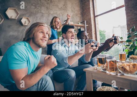 Portrait of four nice attractive cheerful cheery crazy addicted guys playing video game sport cup championship having fun at industrial loft style Stock Photo