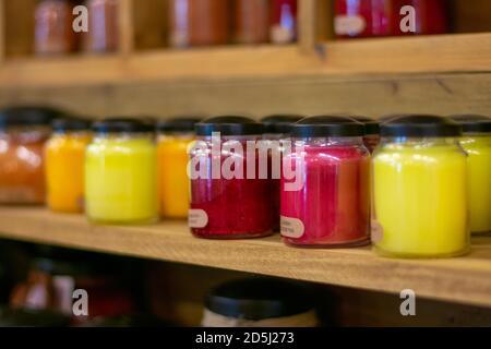 A Light Red Candle on a Shelf Full of Candles in a Farmer's Market Stock Photo