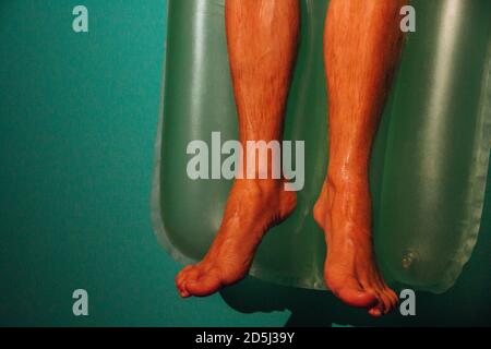 Closeup shot of a male's feet lying on an inflatable mattress Stock Photo