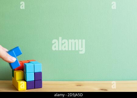 Colorful cube puzzle blocks on wooden desk with green background. Problem solving, creative idea concept Stock Photo