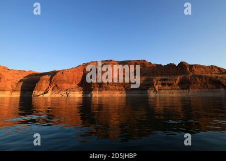 Lake Powell, Arizona, USA. 13th Aug, 2020. Sunset on the waters and red rocks. Lake Powell is a man-made reservoir on the Colorado River in Glen Canyon National Recreation Area and straddles 2 western states Utah and Arizona. It is a major vacation spot, stretching from the beginning of the Grand Canyon in Arizona to southern Utah, Glen Canyon National Recreation Area is graced with scenic views, unique geology and 10,000 years of human history. Activities include boating, fishing, hiking. Lake Powell, is the second largest man made lake in the United States, and is a premier boating destinat Stock Photo