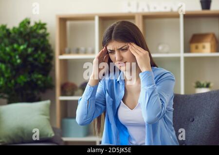 Young stressed woman touching temples with hands and feeling bad Stock Photo