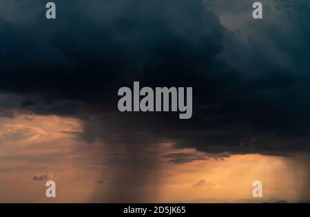 Dark dramatic sky and clouds. Background for death and sad concept. Golden sunlight and black clouds. Thunder and storm sky. Sad and moody sky. Nature Stock Photo