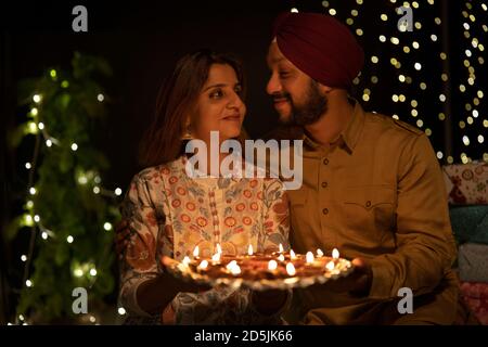 A SIKH MAN AND WOMAN WITH DIYAS IN HAND LOOKING AT EACH OTHER Stock Photo